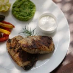 Prato de frango grelhado bem servido com acompanhamentos