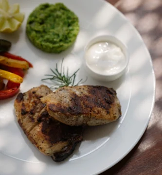 Prato de frango grelhado bem servido com acompanhamentos