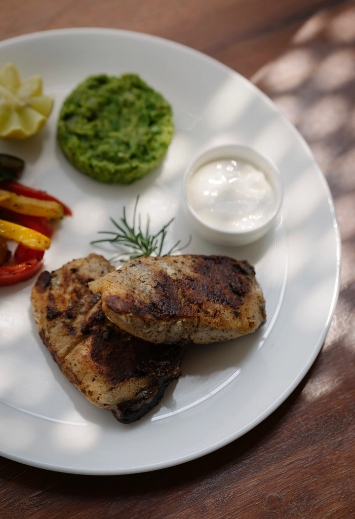 Prato de frango grelhado bem servido com acompanhamentos