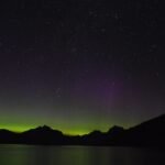 Aurora boreal verde e violeta iluminando o céu noturno