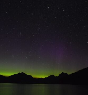 Aurora boreal verde e violeta iluminando o céu noturno