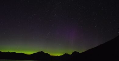 Aurora boreal verde e violeta iluminando o céu noturno