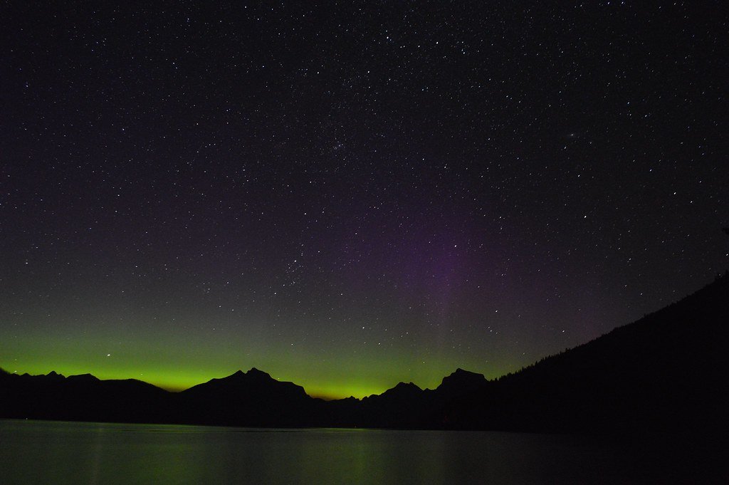 Aurora boreal verde e violeta iluminando o céu noturno